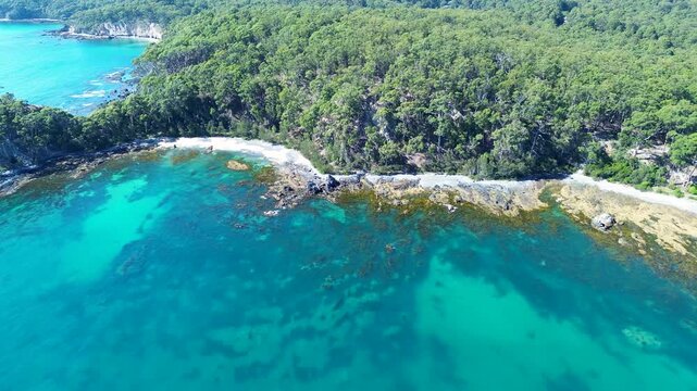 Drone aerial landscape of rocky ocean cove with channel and reef surrounded by bushland forest trees at sandy beach in Batemans Bay headland coastline Australia travel tourism nature wilderness