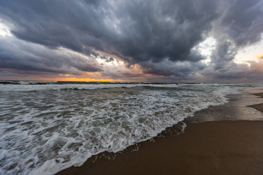 Dramatic storm clouds over rough ocean waves at sandy beach - Powered by Adobe