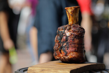 Roasted beef knuckle on a wooden table outside on a sunny day
