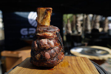 Roasted beef knuckle on a wooden table outside on a sunny day