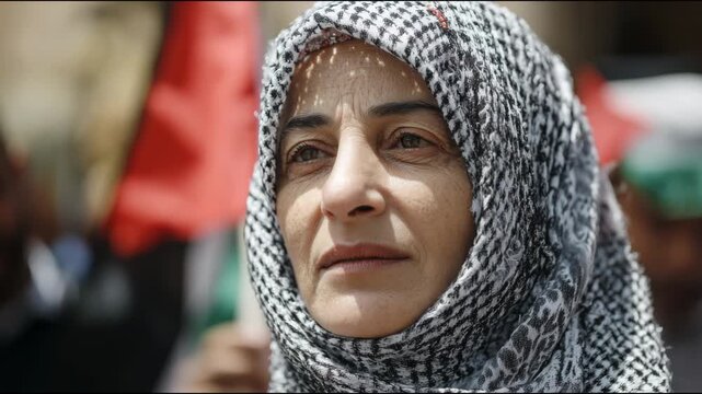 Close-up of a palestinian woman wearing a keffiyeh and speaking during a political demonstration