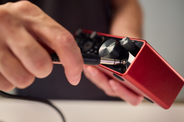 Preparation scene of connecting instrument cable to audio interface for recording, Detailed view of...