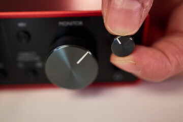 Adjusting audio controls, Precise handling of control knobs on audio equipment during setup, Fingers align control dials on audio interface for optimal sound calibration © Евгений Вершинин