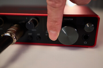 Adjusting audio controls, Precise handling of control knobs on audio equipment during setup, Fingers align control dials on audio interface for optimal sound calibration