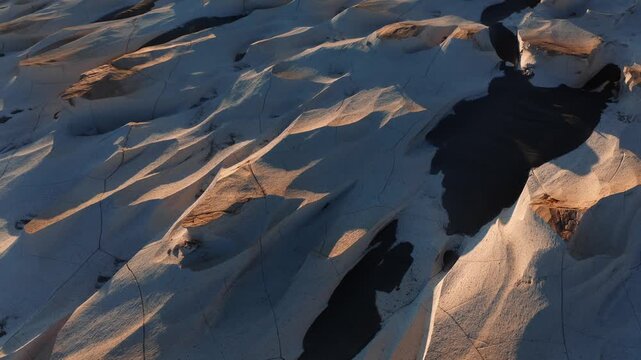 Aerial of uneven pumice stone surface forming natural abstract shapes in arid landscape