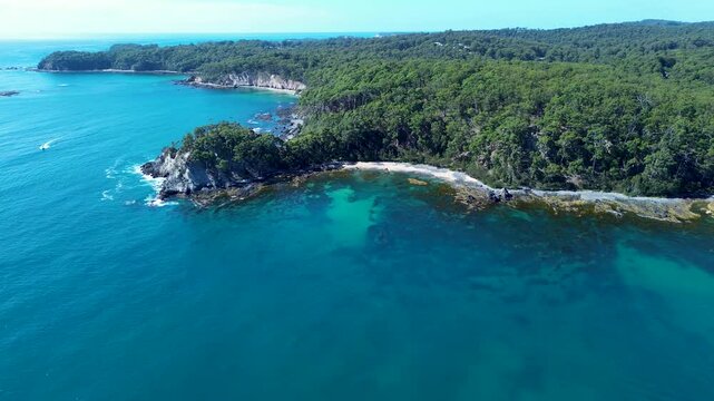 Drone aerial landscape of rocky seaside cove sandy beach headland with bushland trees and clear ocean reef along natural coastline of Batemans Bay in Australia hiking trails travel tourism holidays