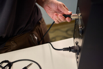 Setting up audio connection professionally, Attaching sound cable to subwoofer in studio, Closeup of hands securing audio cable into subwoofer in recording studio setting © Евгений Вершинин