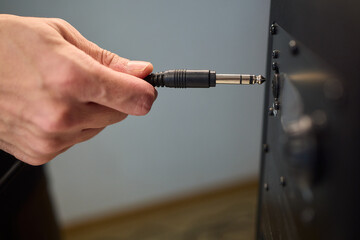Setting up audio connection professionally, Attaching sound cable to subwoofer in studio, Closeup of hands securing audio cable into subwoofer in recording studio setting © Евгений Вершинин