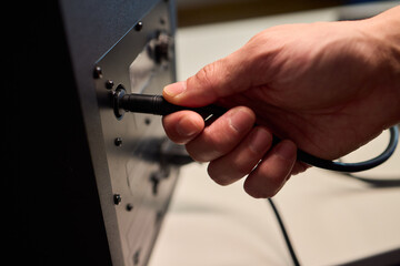Setting up audio connection professionally, Attaching sound cable to subwoofer in studio, Closeup of hands securing audio cable into subwoofer in recording studio setting © Евгений Вершинин