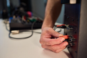 Setting up audio connection professionally, Attaching sound cable to subwoofer in studio, Closeup of hands securing audio cable into subwoofer in recording studio setting © Евгений Вершинин