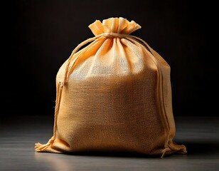 A closed burlap sack with a drawstring closure on a wooden surface against a dark backdrop