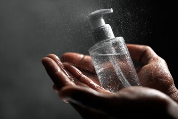 Closeup of hands applying alcohol sanitizer gel in a clean environment for hygiene during the pandemic at an indoor setting in the evening