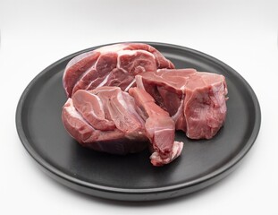 Fresh raw beef meat pieces on black plate isolated on white background for cooking