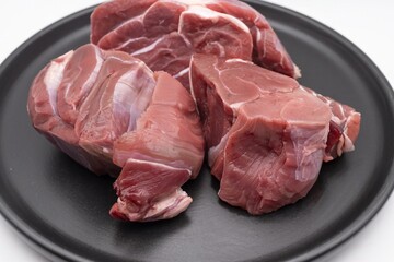 Fresh raw beef meat pieces on black plate isolated on white background for cooking