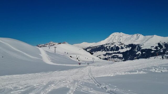 View over the winter sports paradise of Adelboden-Lenk, Switzerland. Snow-covered mountains stretch into the distance as skiers and snowboarders enjoy a bright sunny winter day