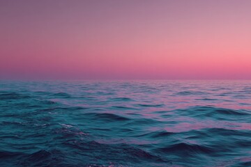 Obraz premium Vivid blue ocean harmonizes with soft pink sky during twilight, creating a serene and beautiful coastal atmosphere at dusk