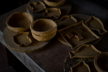 Handcrafted clay pottery pieces arranged on wooden table, showcasing various shapes and sizes. earthy tones and textures highlight artisanal quality of work