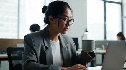 Smiling professional business people and corporate executives sit at office desks working on laptops and computers while using technology for their jobs in a collaborative work environment - Powered by Adobe