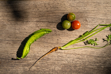 Fresh green vegetables and colorful tomatoes on wooden surface evoke sense of healthy eating and nature bounty. vibrant colors and textures create appealing composition