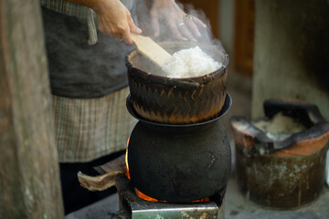 Steaming rice in traditional pot over open flame, showcasing culinary techniques and cultural heritage. steam rises, creating warm and inviting atmosphere