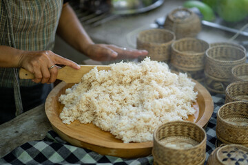 Freshly cooked rice being prepared in traditional kitchen, showcasing process of serving. warm, inviting atmosphere highlights cultural culinary practices