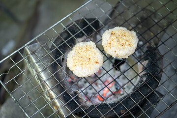 Grilled rice cakes cooking on charcoal grill, showcasing delicious outdoor cooking experience. golden brown texture adds to appetizing look