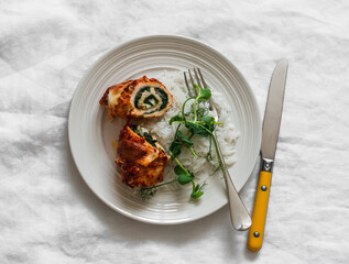 Chicken rolls stuffed with spinach, mozzarella and rice on a light background, top view