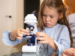 Little girl focusing on discovery with a microscope, exploring science and education