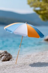 a beach umbrella with striped orange and blue colors on the sand by the sea, a summer vacation concept.