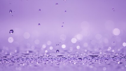 Water droplets falling on a surface creating a blurred purple background with bokeh effect