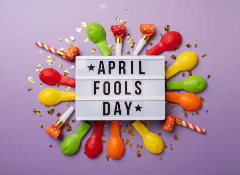 April Fool&rsquo;s Day sign surrounded by colorful balloons, party blowers, and gold confetti on a pastel background perfect for april fool's day, joking, prank, and comedy