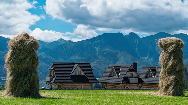 Timelapse of clouds moving over Tatra Mountains with haystacks and houses in Furmanowa