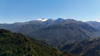 Fototapeta premium Panoramic aerial view of Artvin mountains in Turkey – lush green hills, rugged terrain, and snow-capped peaks under a clear blue sky.