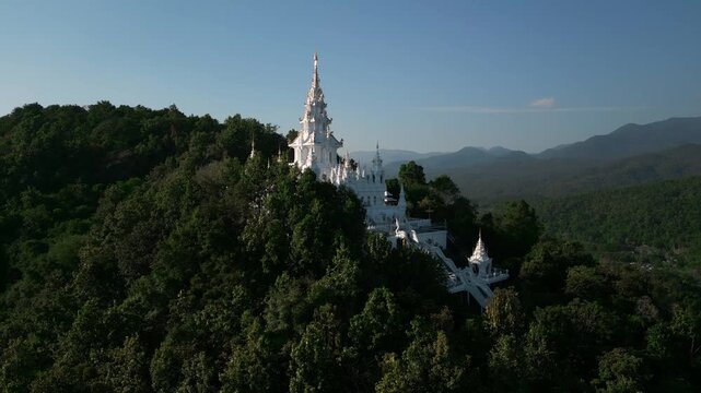 Aerial drone footage of the Loha Prasat Sri Mueang Pong pagoda temple in Chiang Mai, Thailand, on a sunny day, showcasing traditional architecture surrounded by nature