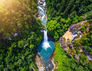 Lush green nature landscape featuring a majestic long river flowing over rocks from a high mountain peak in a summer forest park