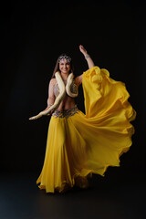 Woman dances with snake in vibrant costume in a studio setting during an evening performance