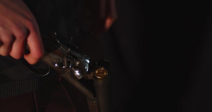 Close up of hands breaking open a double barreled shotgun and loading it with a 12 gauge shell. A shot and discarded casing gets removed from the chamber.