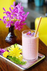 A glass of blueberries smoothie and violet flowers decorated on topping	