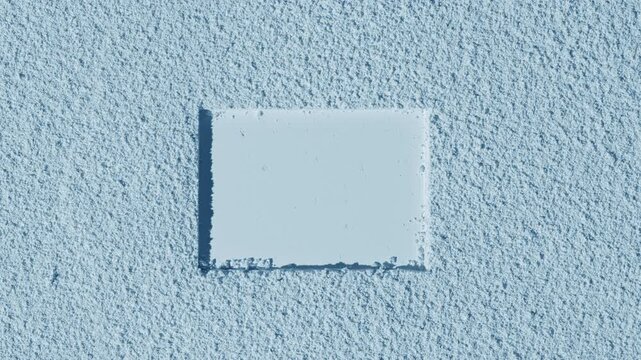 Top-down capture of a pale blue delicate sifted powder surface with a rectangle imprint, illuminated by orbiting directional light producing dynamic shadows