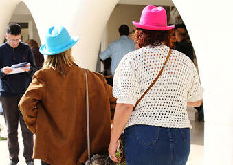 Mujeres pareja homosexual con sombrero de color azul y rosa fucsia en fiesta al aire libre