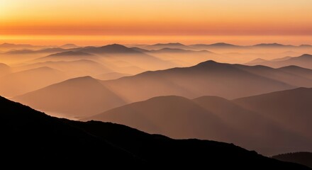 Misty mountain range at sunrise with orange sky
