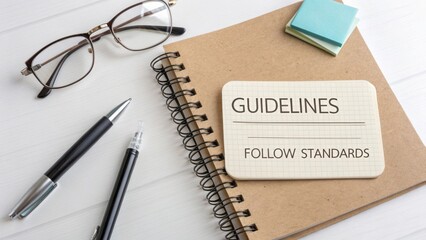 Notebook with Guidelines for Standards, Glasses, Pens, and Sticky Notes on a Light Wooden Table Surface