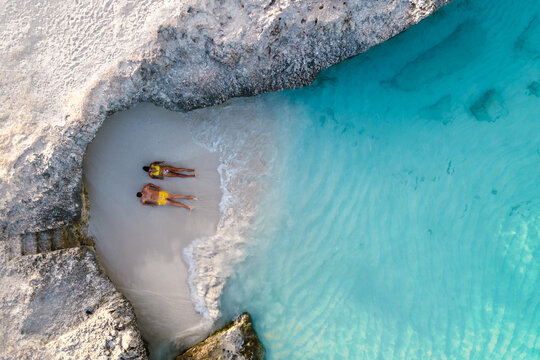 Two people unwind on the soft sands of Tres Trapi Beach in Noord, Aruba. With crystal-clear waters, this beautiful spot offers a perfect setting for relaxation and island exploration.
