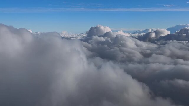 Dreamy Cloudscape captured from a jet cockpit while flying at sunset over an endless blanket of clouds under a blue sky.