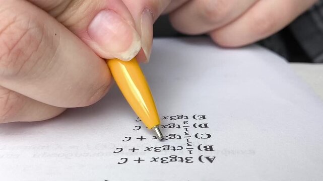 A woman solves math examples. A woman runs a pen over paper and chooses an answer in a math exam.
