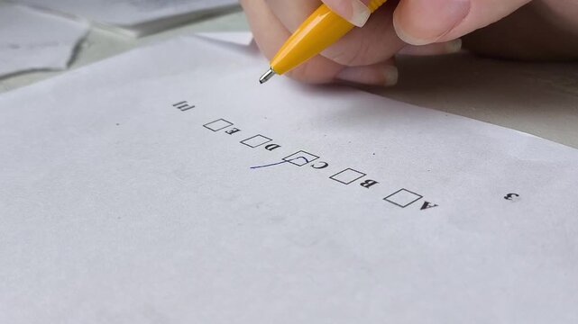 A tick next to the correct answer in the exam sheet, next to a hand and a pen. Concept of exams at school, university, college. Training