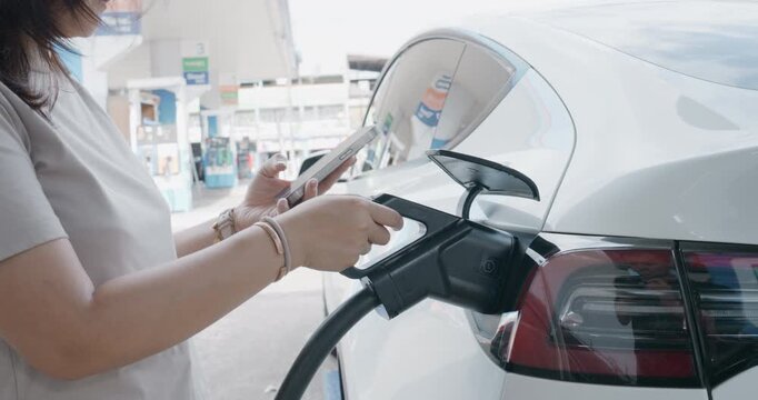Business woman use smartphone application EV car charge outdoor station sustainability transport technology