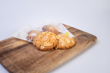 Traditional almond cookies with almond flakes on the wooden cutting board. Image closed up view.