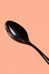 Black spoon against peach background