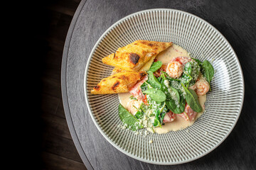 Shrimp with creamy sauce, fresh spinach and toasted bread served on plate, top view